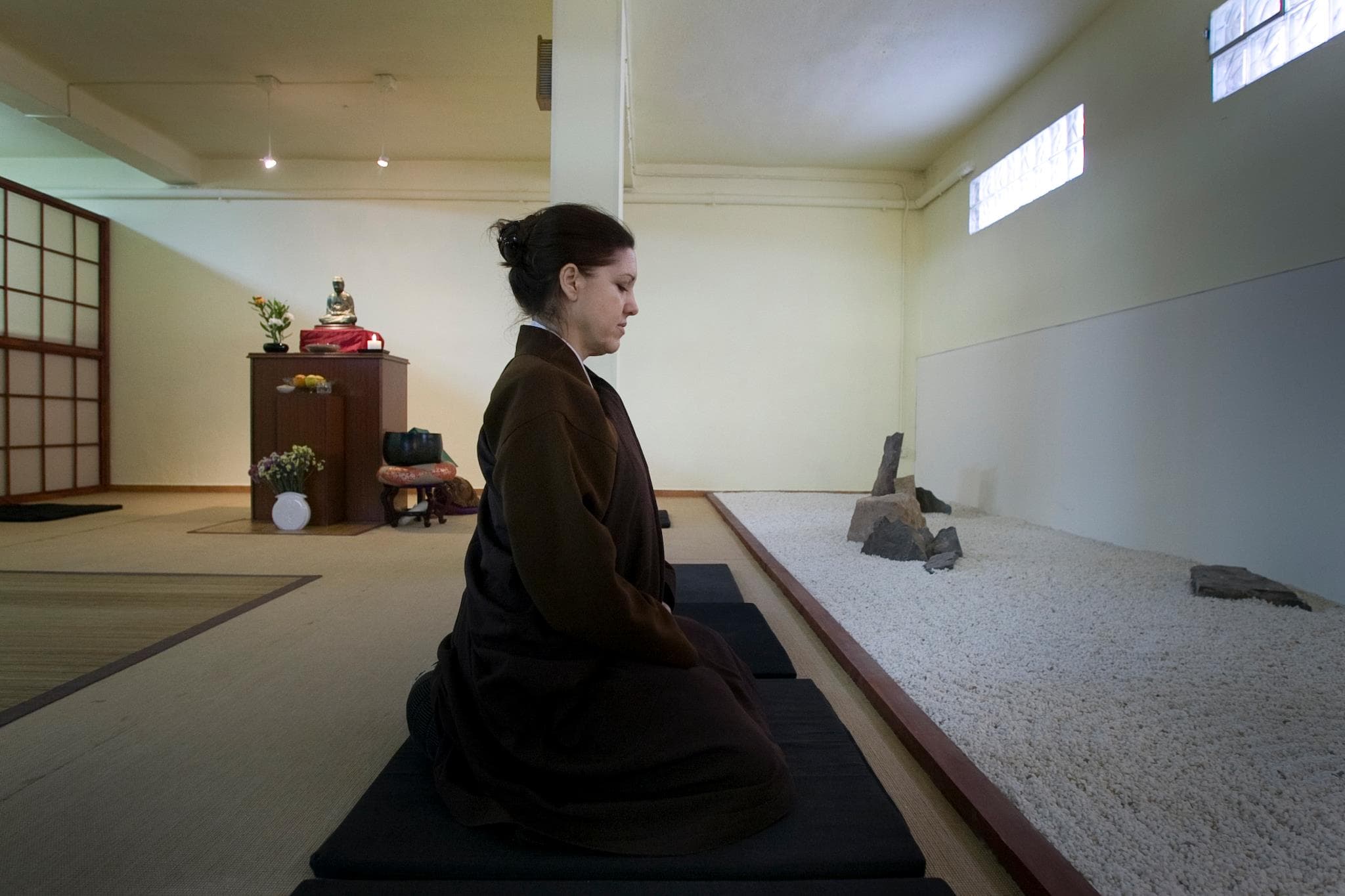Mar practica zazen sentada en el dojo, junto a un jardín de piedras.
