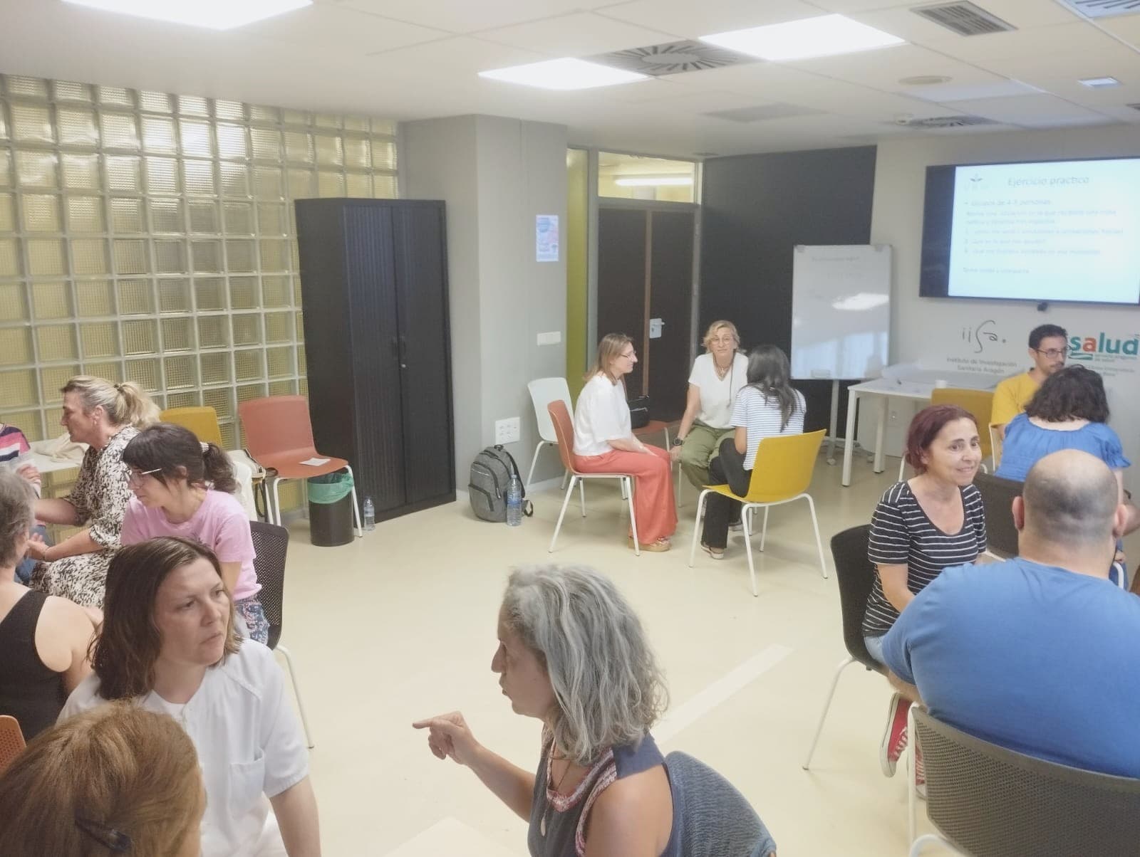 Profesionales dialogan en pequeños grupos durante una formación en una sala hospitalaria.