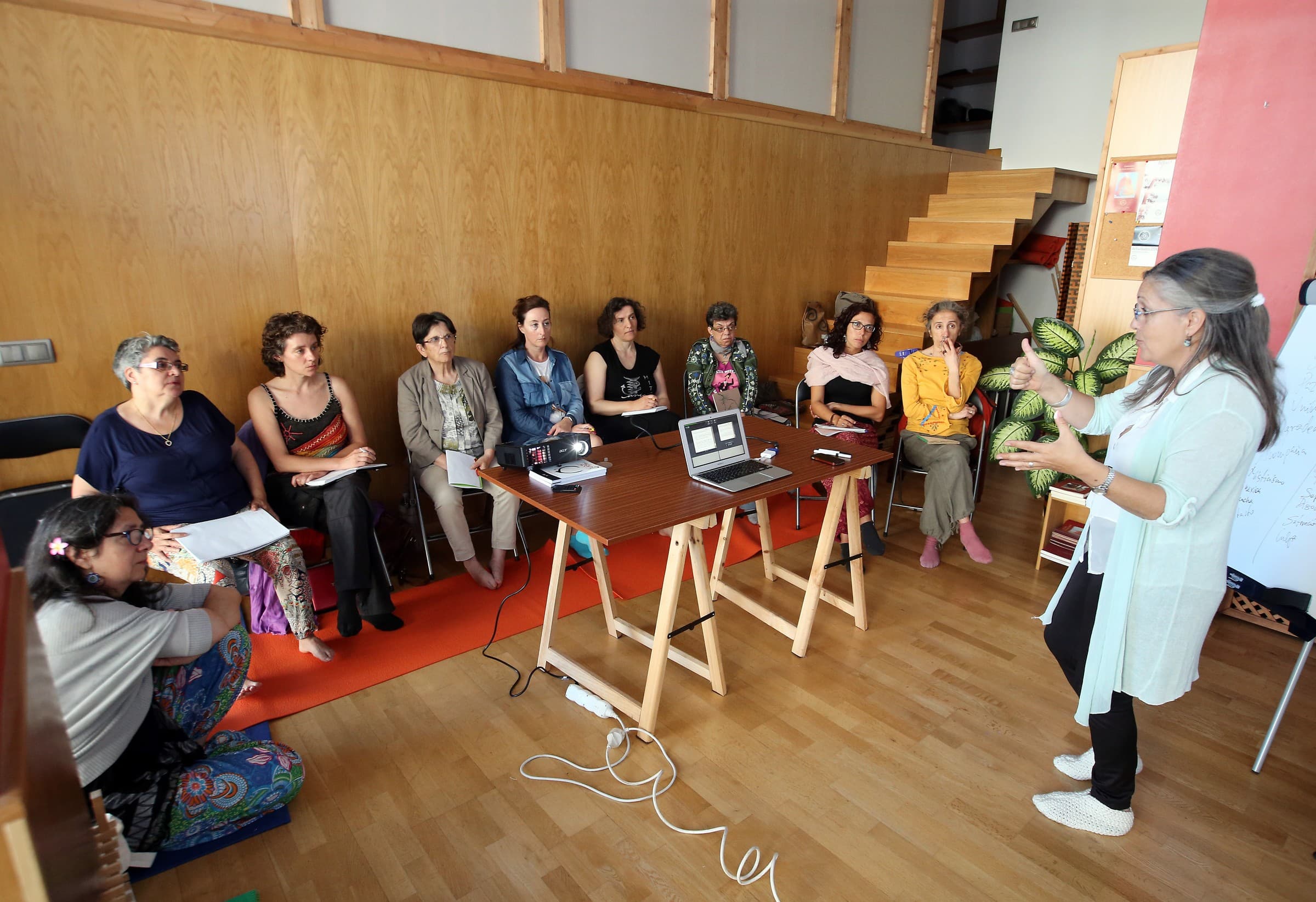 Una docente explica un contenido a un pequeño grupo durante un taller presencial.